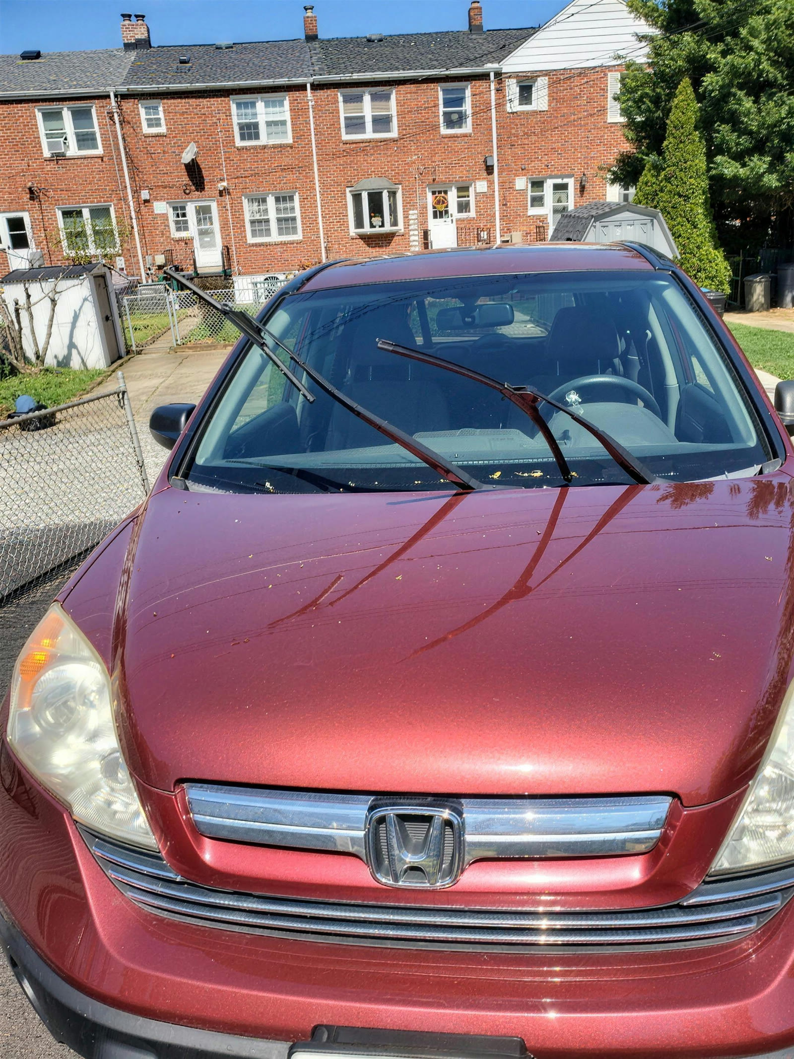 Front of a dark red 2008 Honda CR-V with hazed headlights and dull paint, before detailing